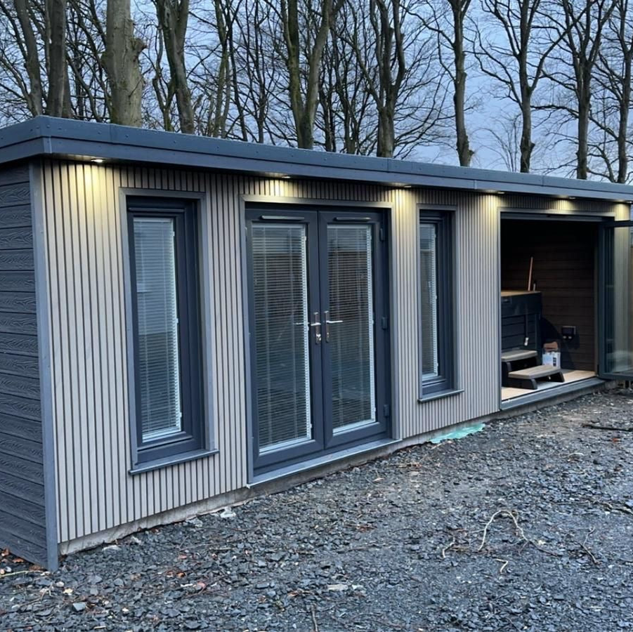 Modular building with large glass doors and windows in a wooded area.
